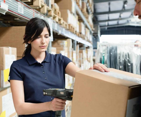 Warehouse workers using barcode scanner on box in distribution warehouse